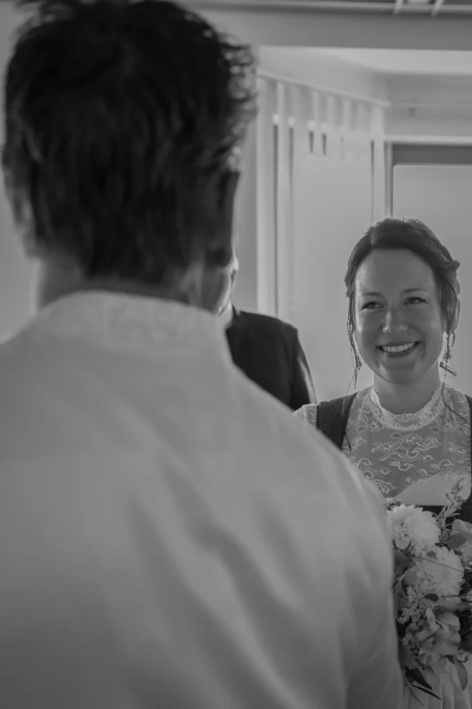 Braut lächelt den Bräutigam an, nachdem sie das Standesamt betreten hat. Schwarz/weiß Foto. Fotografiert von hochzeitsfotograf-bamberg.net.