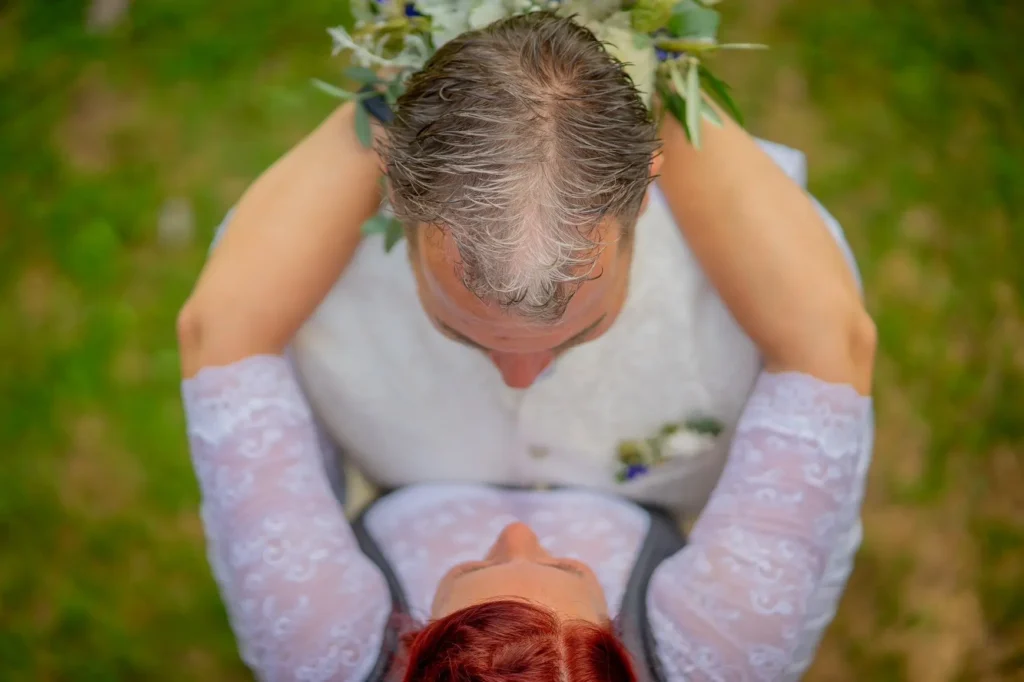 Brautpaar steht Brust an Brust und umarmen sich. Von oben fotografiert. Braut hält den Brautstrauß hinter dem Kopf des Bräutigams. Fotografiert von hochzeitsfotograf-bamberg.net