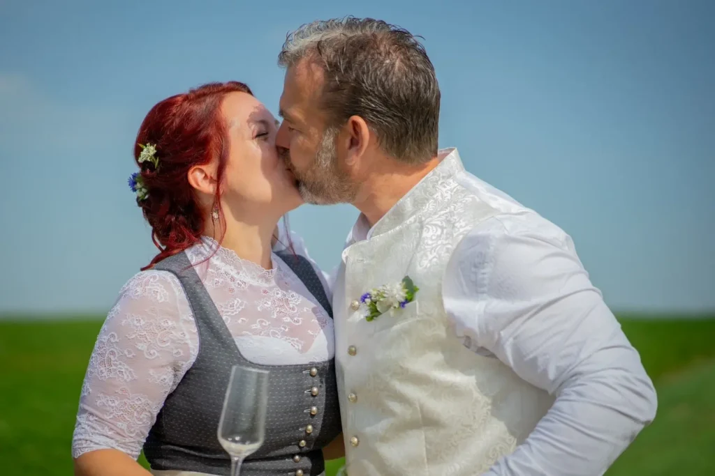 Bräutigam küsst die Braut vor einem strahlend blauen Himmel. Fotografiert von hochzeitsfotograf-bamberg.net