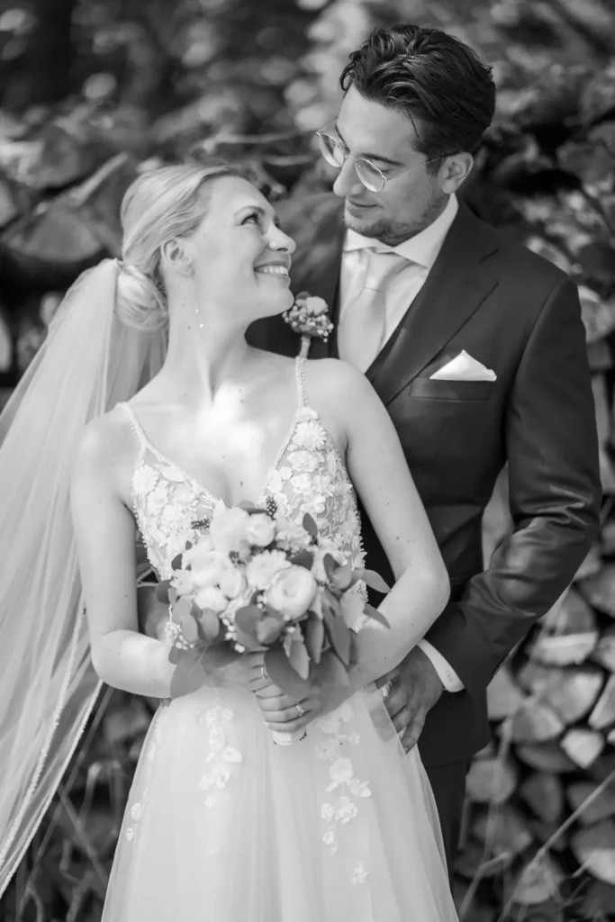 Brautpaarshooting. Braut steht vor dem Bräutigam. Braut dreht sich nach über die Schulter nach hinten um und lächelt den Bräutigam an. Fotografiert von hochzeitsfotograf-bamberg.net