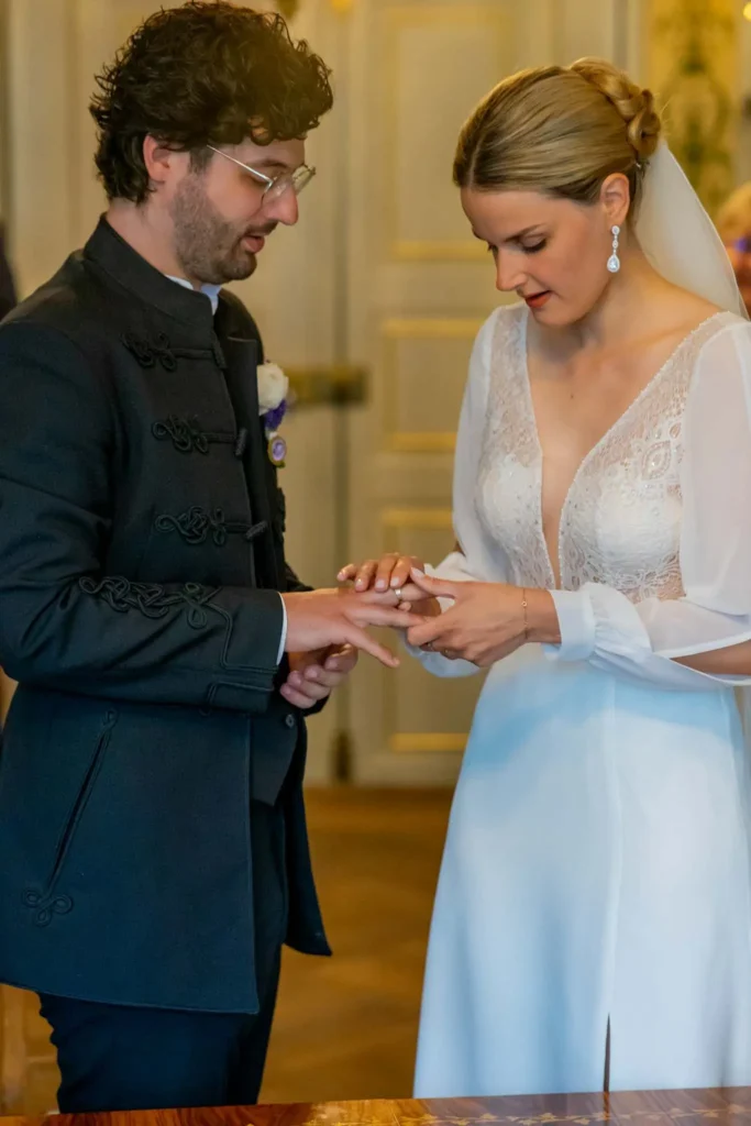 Braut steckt dem Bräutigam den Trauring an den Finder. Beide schauen den Ring an. Fotografiert von hochzeitsfotograf-bamberg.net