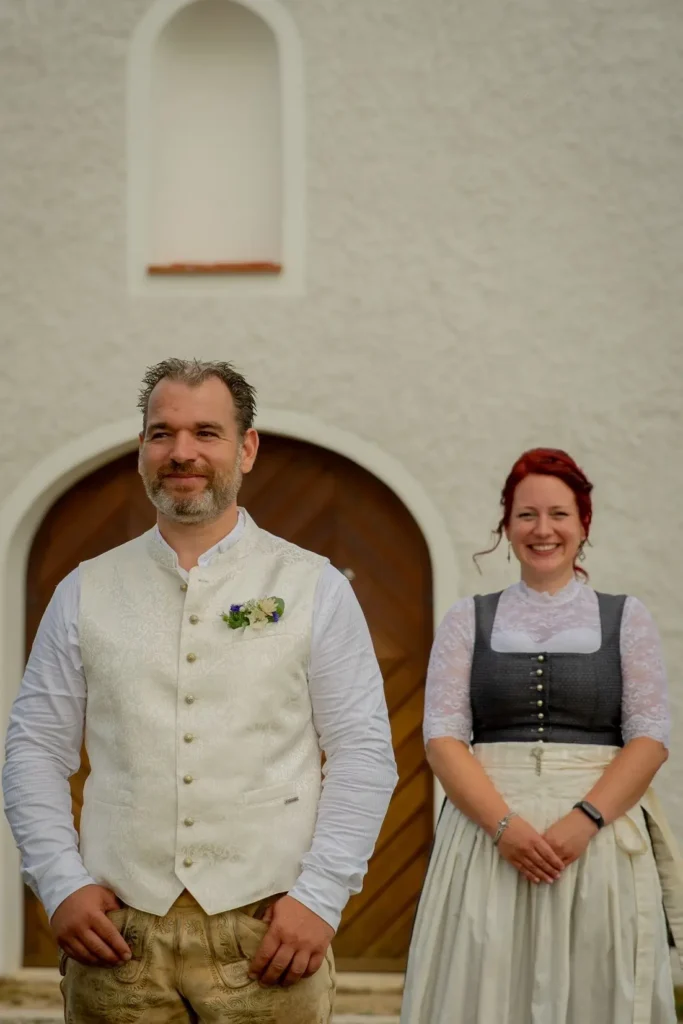 First Look Shooting. Braut steht hinter dem Bräutigam und lächelt in die Kamera. Fotografiert von hochzeitsfotograf-bamberg.net